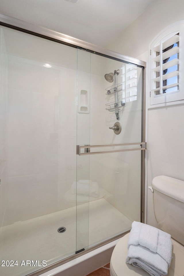 bathroom featuring toilet and an enclosed shower