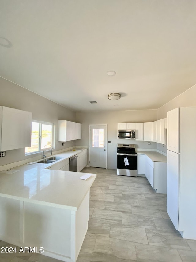 kitchen with kitchen peninsula, stainless steel appliances, sink, white cabinets, and lofted ceiling