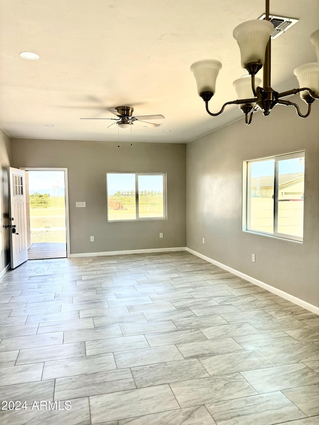 spare room with ceiling fan with notable chandelier and a healthy amount of sunlight