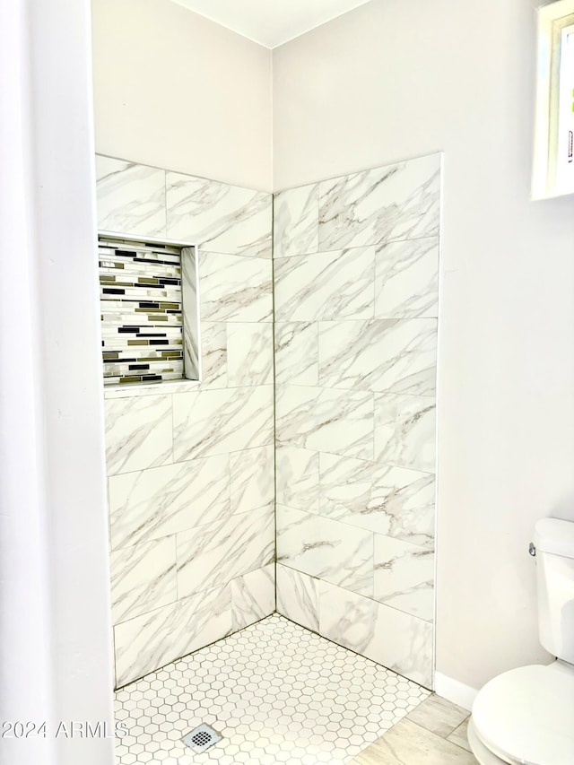 bathroom featuring tiled shower and toilet