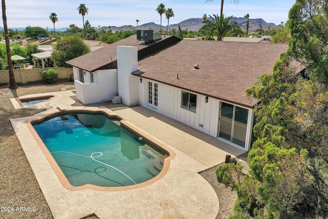 view of swimming pool with a mountain view, a hot tub, and french doors