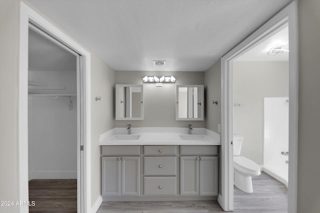 bathroom with hardwood / wood-style flooring, vanity, toilet, and a textured ceiling