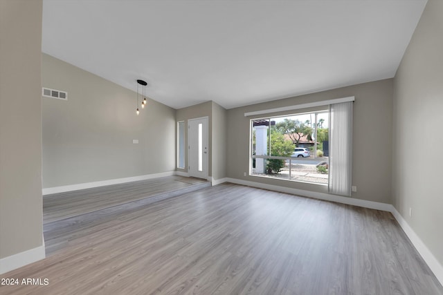 unfurnished room featuring vaulted ceiling and light hardwood / wood-style flooring