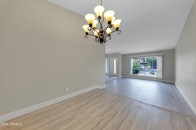 empty room featuring an inviting chandelier and light hardwood / wood-style floors