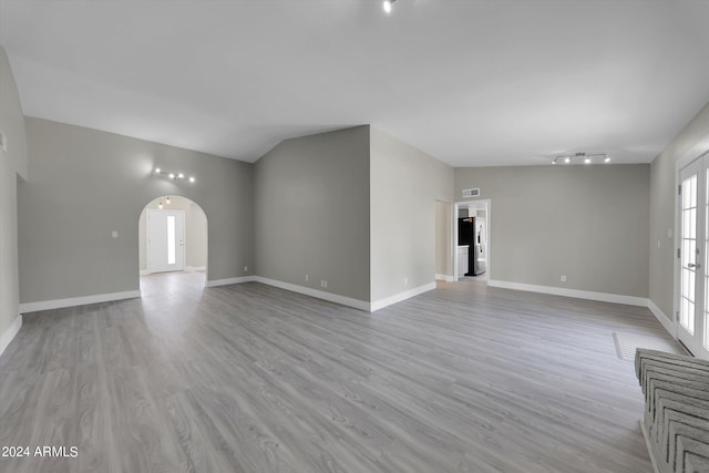 unfurnished living room featuring lofted ceiling and light hardwood / wood-style floors