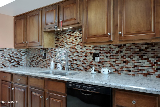 kitchen with black dishwasher, light stone counters, a sink, and decorative backsplash