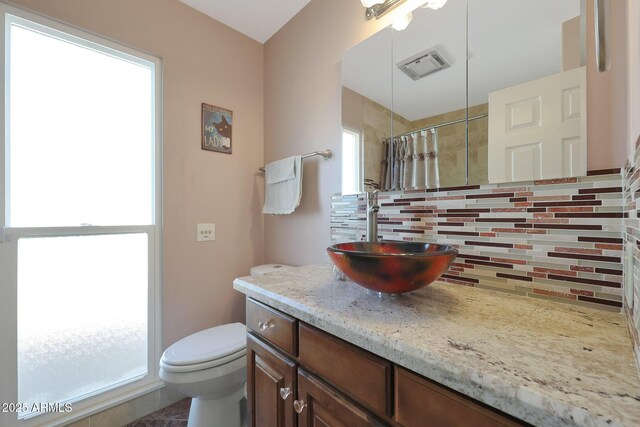 bathroom featuring toilet, a shower with shower curtain, vanity, visible vents, and tasteful backsplash