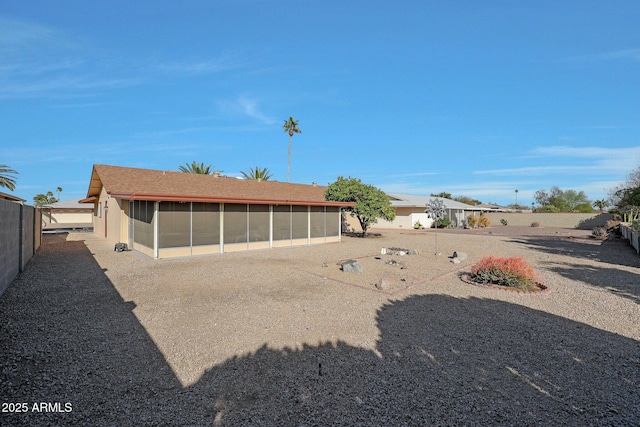 rear view of house featuring a sunroom and fence