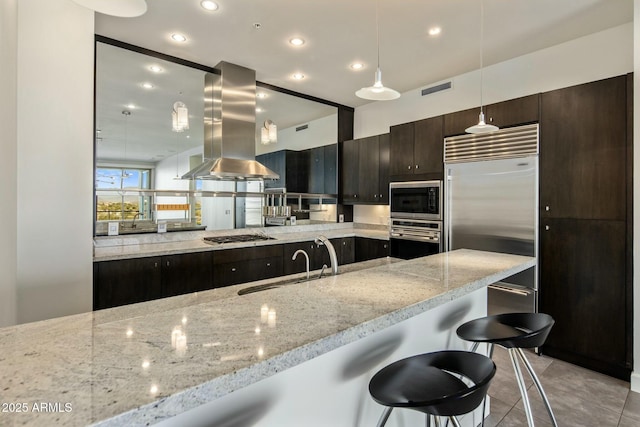 kitchen featuring built in appliances, a breakfast bar, light stone counters, and island exhaust hood