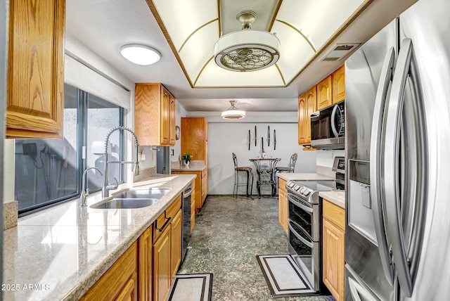 kitchen with appliances with stainless steel finishes, sink, and light stone counters