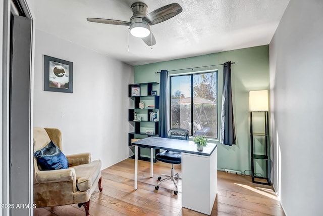 office space with ceiling fan, a textured ceiling, and light wood-type flooring