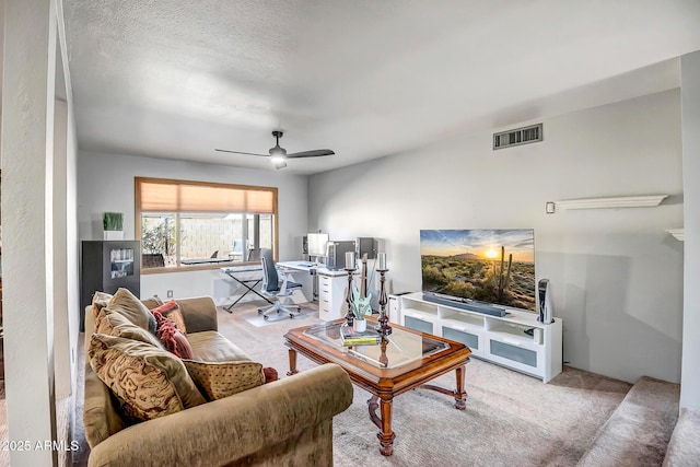 living room featuring ceiling fan, carpet floors, and a textured ceiling