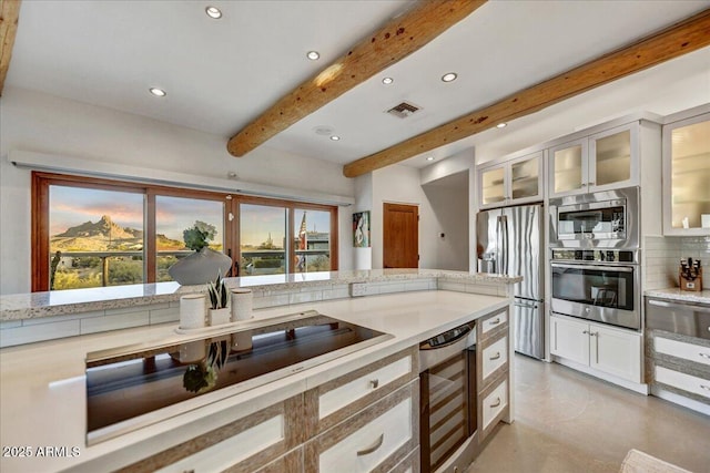 kitchen with visible vents, white cabinets, stainless steel appliances, light countertops, and beam ceiling