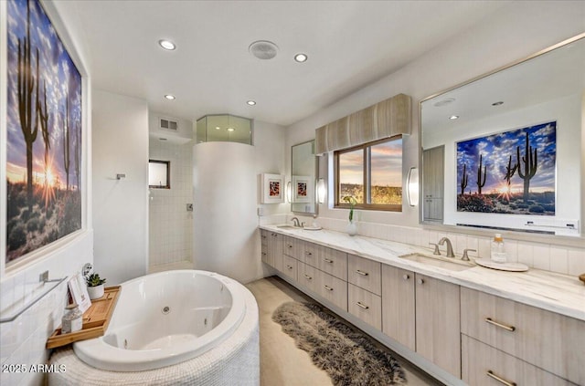 bathroom with double vanity, visible vents, a tile shower, a sink, and a jetted tub