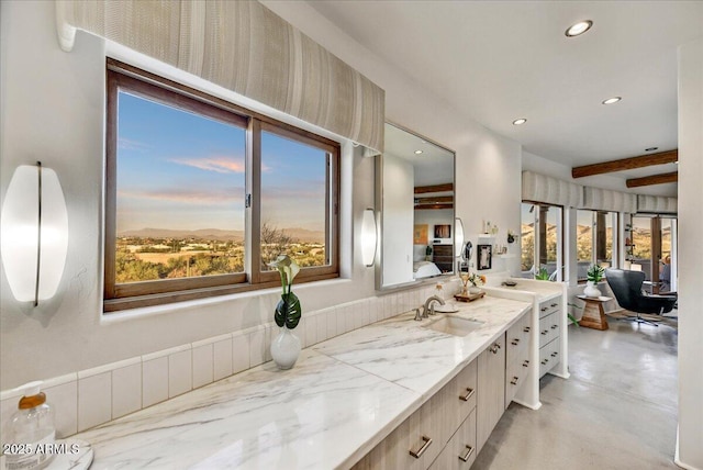 bathroom with a healthy amount of sunlight, finished concrete floors, vanity, and recessed lighting