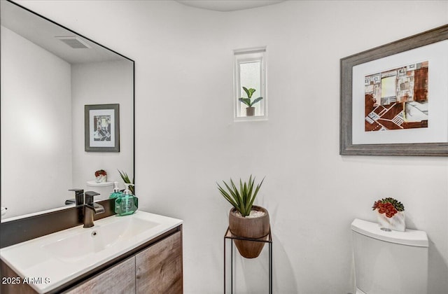 bathroom featuring visible vents, vanity, and toilet