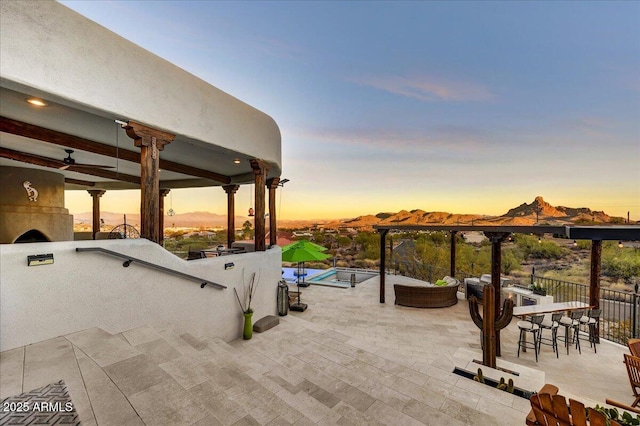 patio terrace at dusk featuring a mountain view and outdoor dry bar