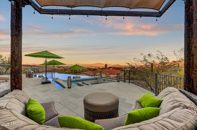 pool at dusk featuring a patio, outdoor lounge area, a fenced in pool, and a hot tub