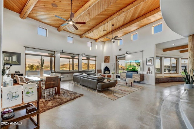 living area featuring wooden ceiling, a healthy amount of sunlight, concrete floors, and beamed ceiling