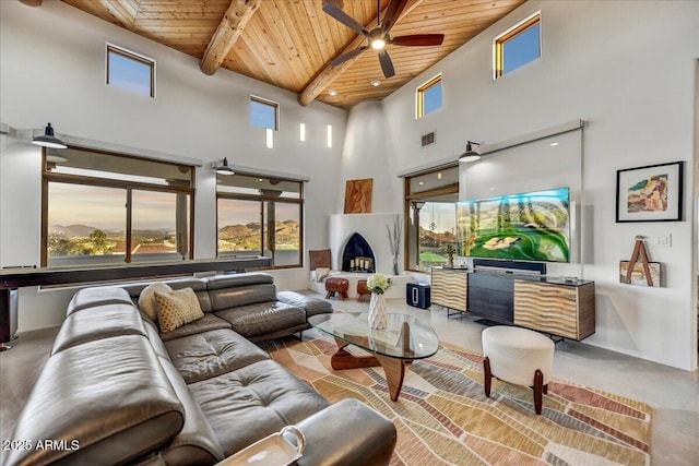 living room featuring visible vents, a towering ceiling, wood ceiling, ceiling fan, and beamed ceiling