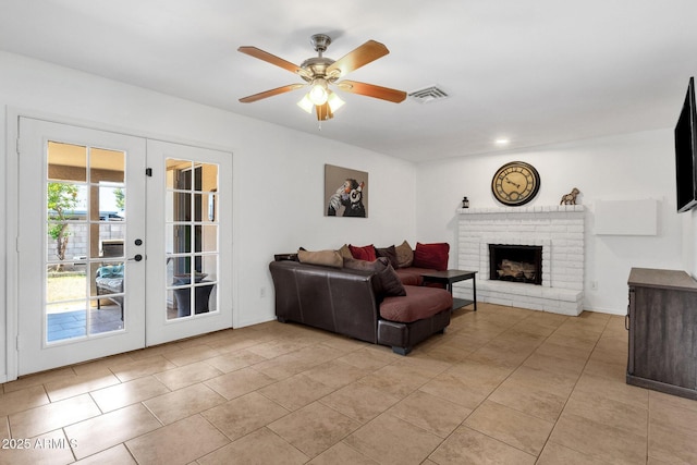 living area featuring french doors, light tile patterned flooring, a ceiling fan, and a brick fireplace