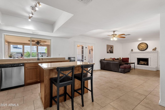 kitchen featuring stainless steel dishwasher, ceiling fan, a sink, a kitchen breakfast bar, and french doors