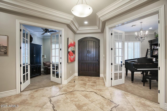 carpeted foyer entrance with ceiling fan with notable chandelier, french doors, and ornamental molding