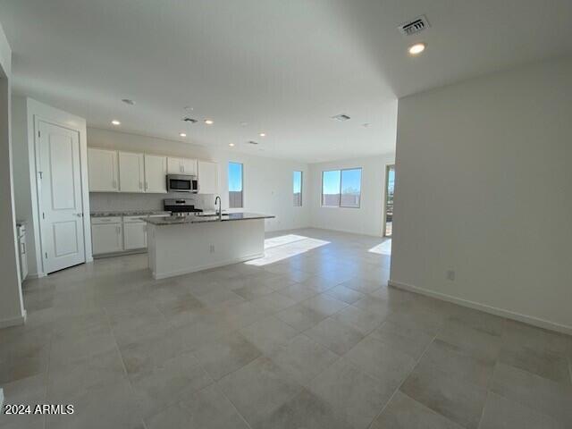 kitchen featuring white cabinetry, electric stove, sink, and an island with sink