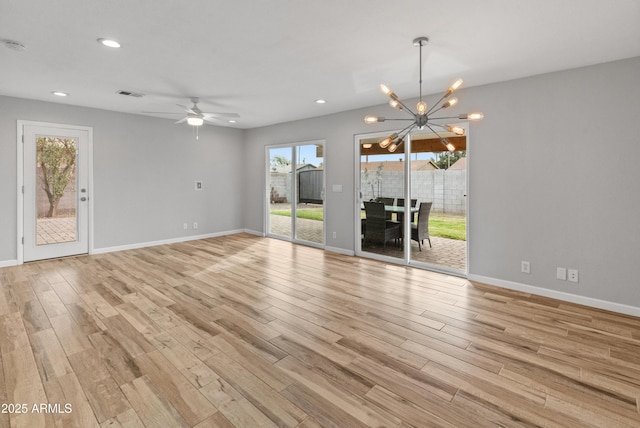 unfurnished living room featuring plenty of natural light, light hardwood / wood-style floors, and ceiling fan with notable chandelier