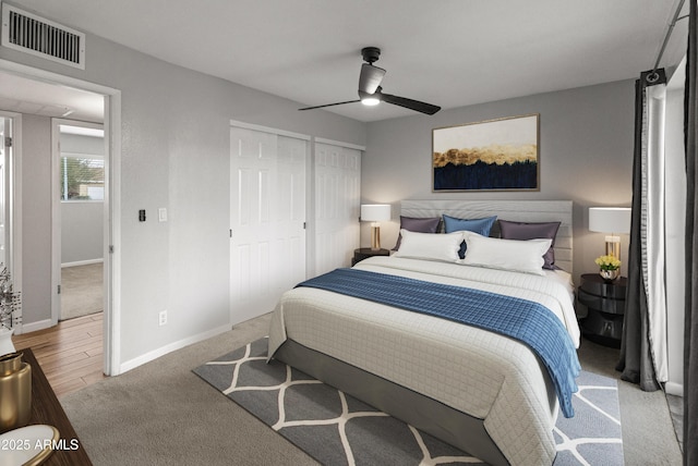 bedroom featuring multiple closets, ceiling fan, and light carpet