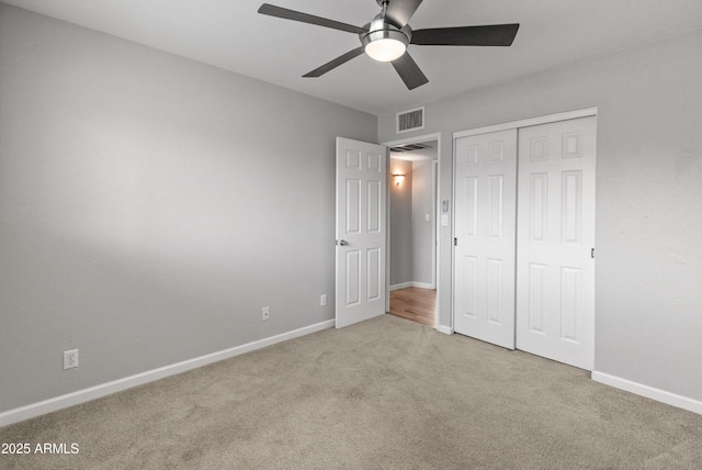 unfurnished bedroom with ceiling fan, a closet, and light colored carpet