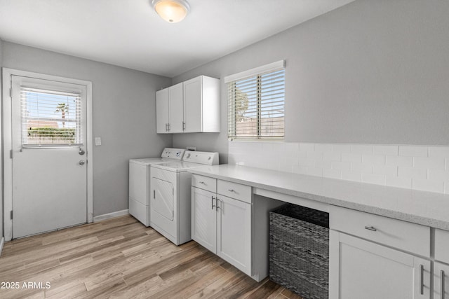 laundry area with cabinets, light wood-type flooring, and washing machine and clothes dryer