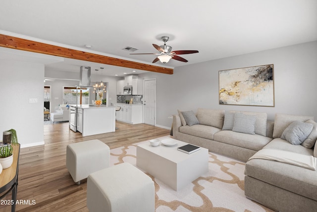 living room featuring ceiling fan with notable chandelier, light hardwood / wood-style floors, and beam ceiling