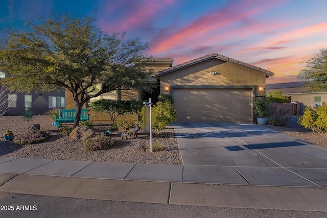 view of front facade with a tiled roof, a garage, driveway, and stucco siding