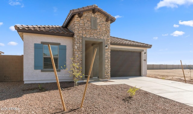 view of front facade with a tiled roof, concrete driveway, stucco siding, stone siding, and an attached garage