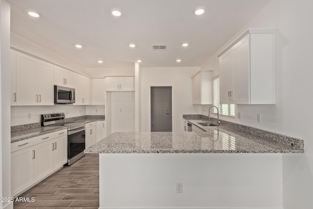 1552 N Pueblo Dr, Apache Junction, AZ 85120 - kitchen with appliances with stainless steel finishes, a peninsula, stone counters, white cabinetry, and recessed lighting
