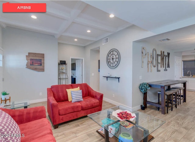 living room featuring sink, beamed ceiling, coffered ceiling, and light wood-type flooring