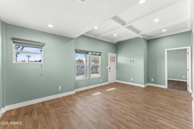 unfurnished room featuring light hardwood / wood-style floors, beam ceiling, a wealth of natural light, and coffered ceiling