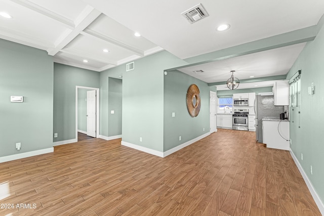 unfurnished living room with beamed ceiling, an inviting chandelier, and light hardwood / wood-style flooring