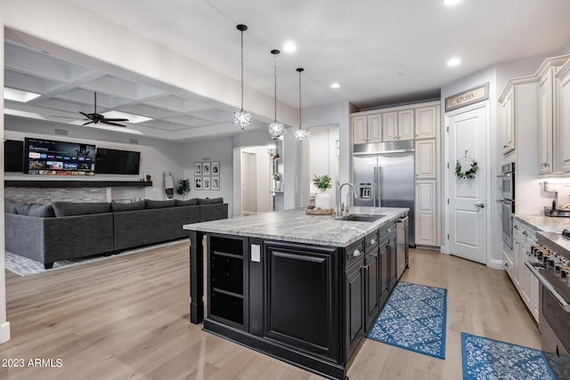 kitchen featuring light wood-type flooring, coffered ceiling, pendant lighting, beamed ceiling, and an island with sink