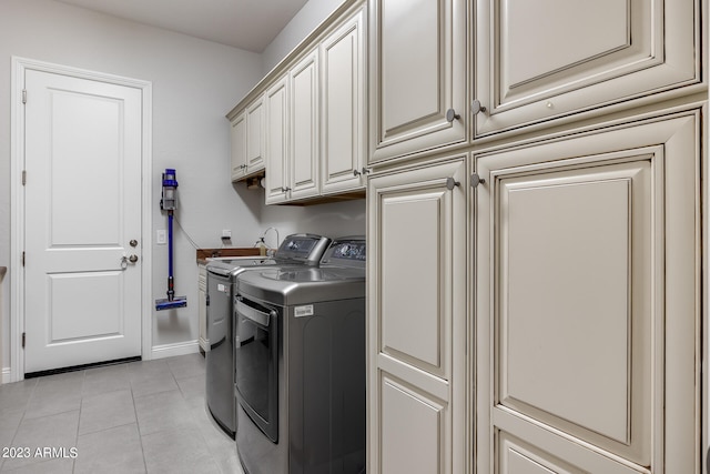 laundry room with cabinets, light tile patterned floors, and washer and dryer