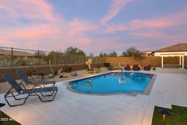 pool at dusk featuring a patio and an outdoor hangout area