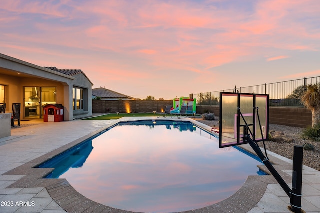 pool at dusk with a patio area