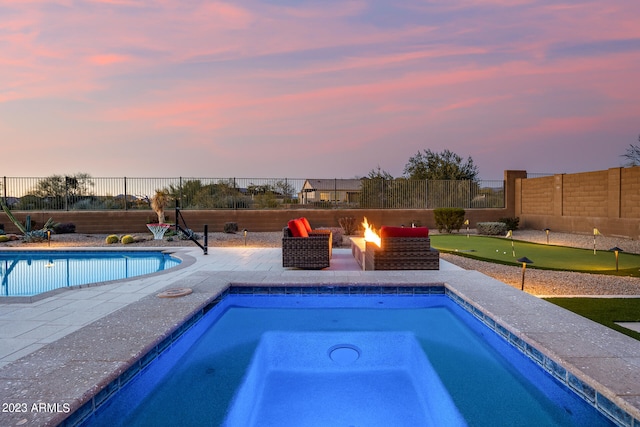 pool at dusk featuring an in ground hot tub, a fire pit, and a patio area