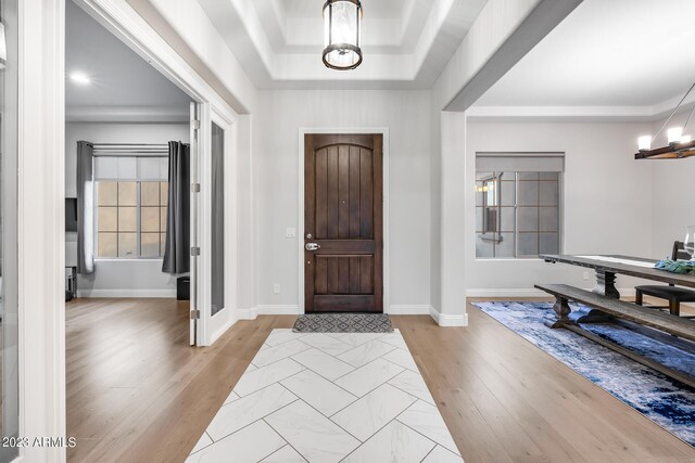 foyer featuring light wood-type flooring and a tray ceiling