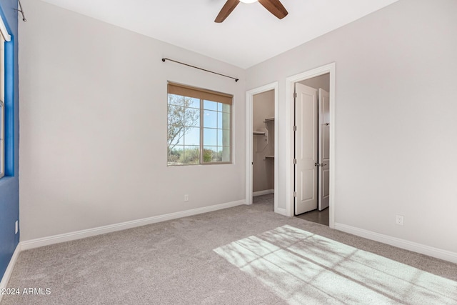 unfurnished bedroom featuring carpet flooring, ceiling fan, a closet, and a spacious closet