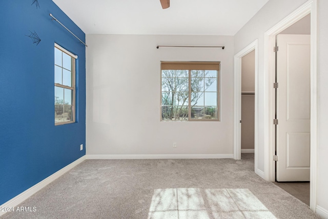 unfurnished bedroom with light carpet, multiple windows, and ceiling fan