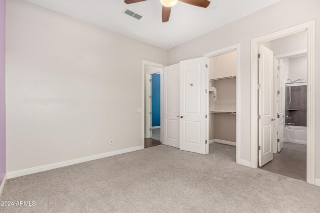 unfurnished bedroom with ensuite bath, ceiling fan, a spacious closet, light colored carpet, and a closet