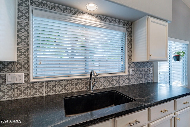 kitchen with sink, white cabinetry, a wealth of natural light, and dark stone countertops