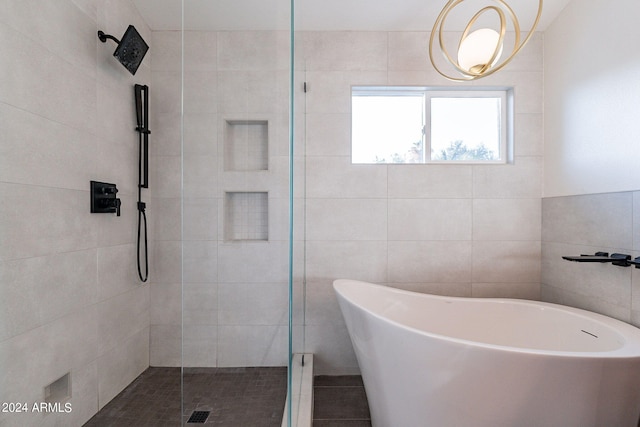 bathroom featuring shower with separate bathtub and tile walls